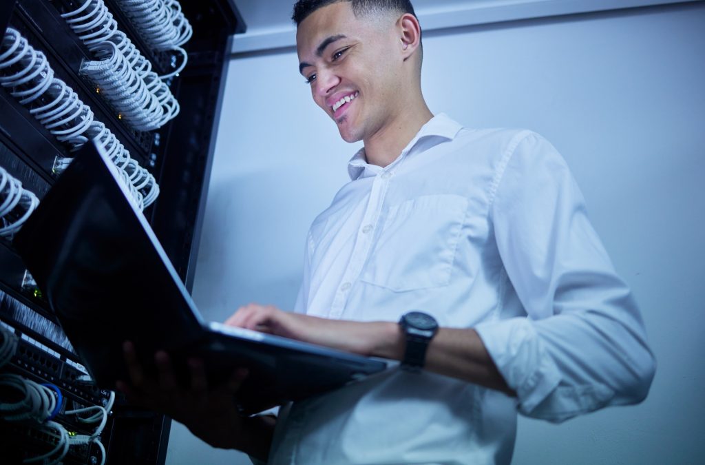 Laptop, server room technician and happy man smile for cloud computing success, data center insigh